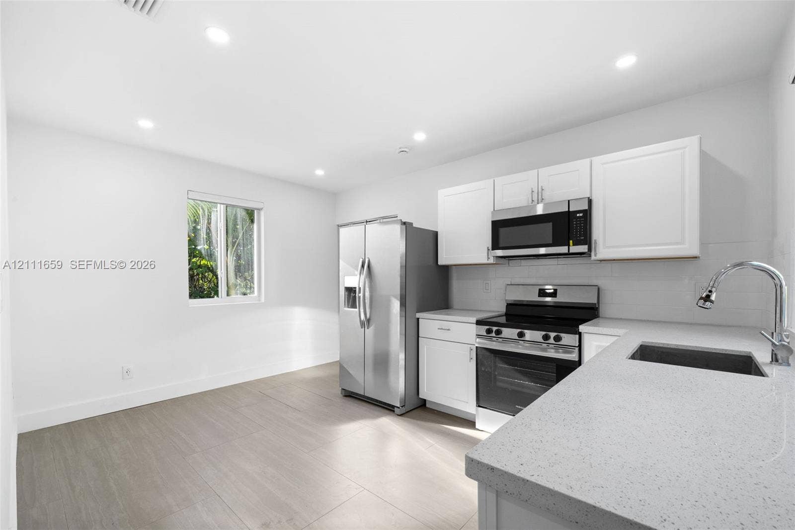 338 Taylor Street, #2, Hollywood, Hollywood, FL 33019 Kitchen featuring white shaker-style cabinetry, solid-surface countertops, recessed lighting, wood-finish flooring, and stainless steel appliances