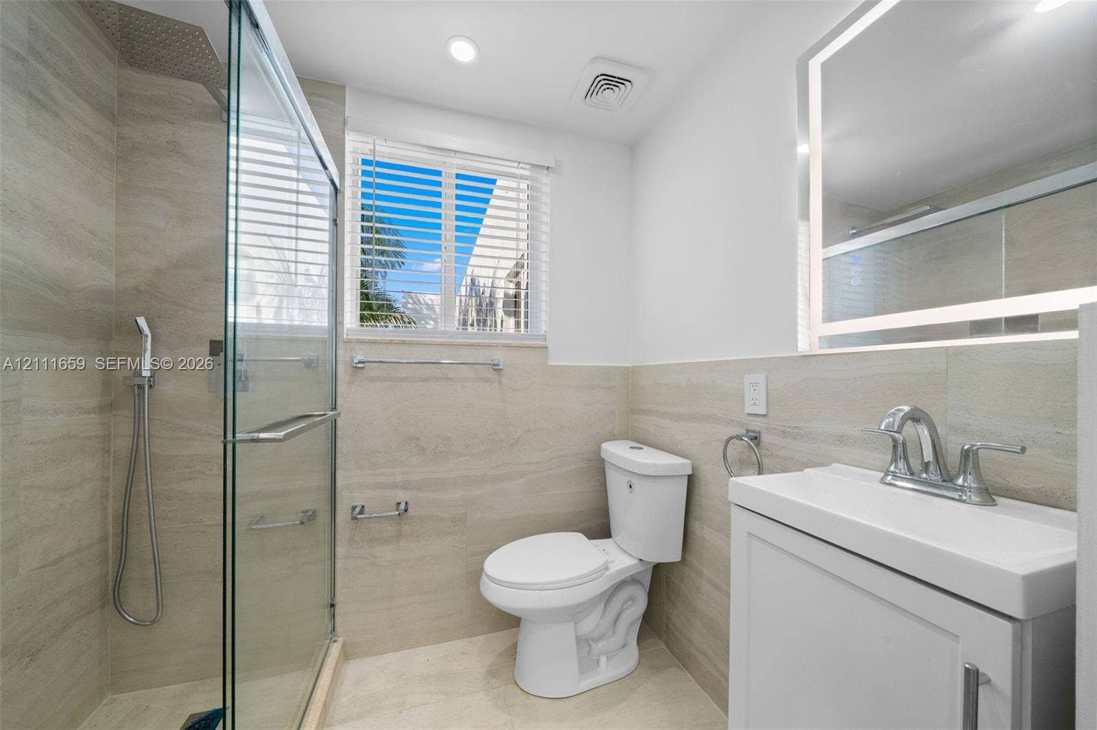 338 Taylor Street, #2, Hollywood, Hollywood, FL 33019 Bathroom featuring walk-in shower with glass enclosure, stone-finish wall tile, illuminated vanity mirror, and white cabinetry