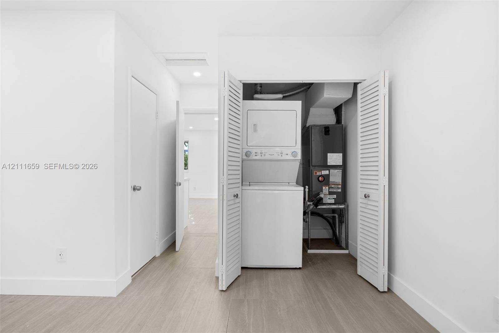 338 Taylor Street, #2, Hollywood, Hollywood, FL 33019 Laundry closet featuring stackable appliances and louvered folding doors, wood-finish flooring, and recessed ceiling lighting