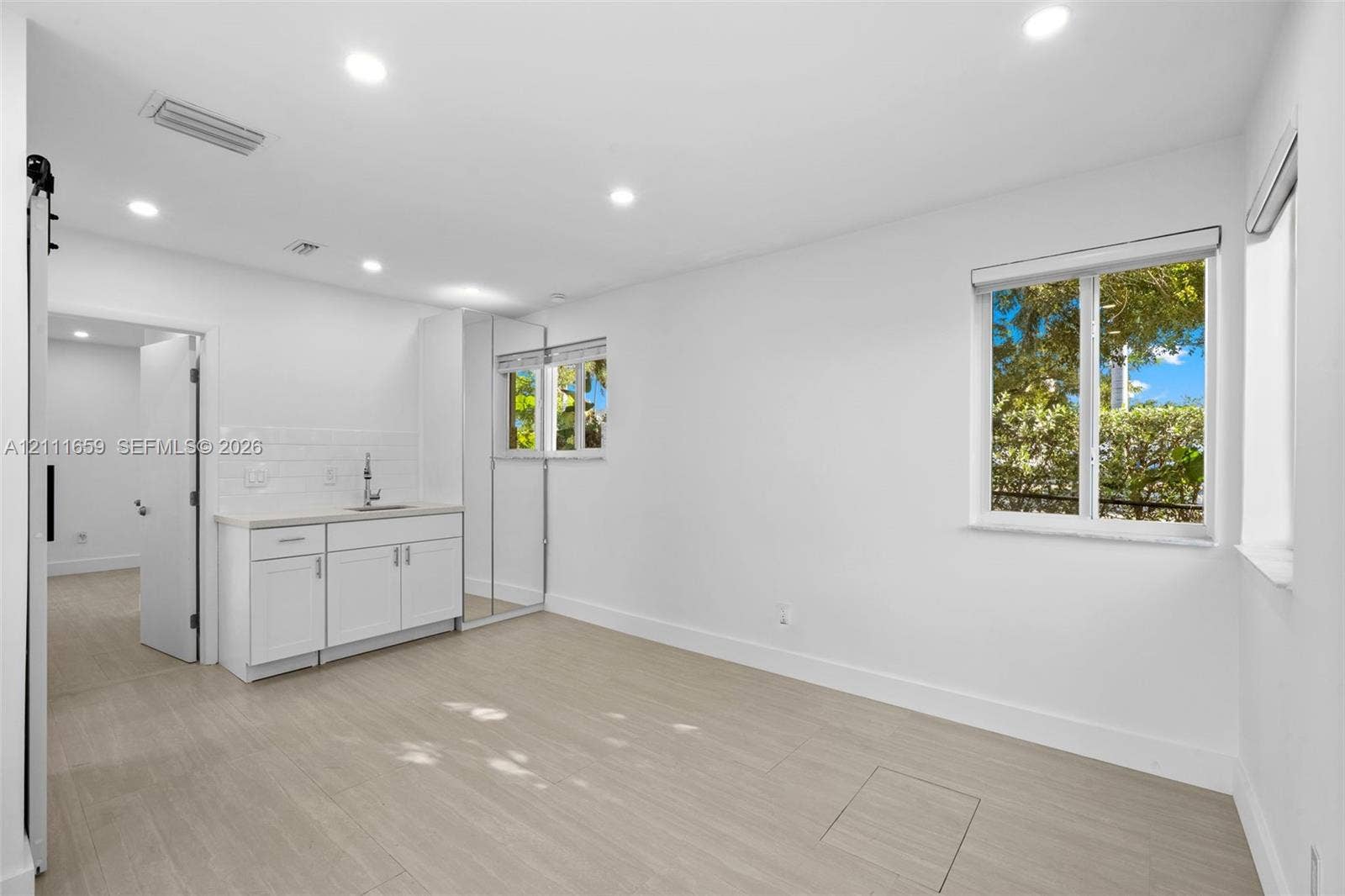 338 Taylor Street, #2, Hollywood, Hollywood, FL 33019 Interior space featuring wood-finish flooring, recessed lighting, white cabinetry with a sink, subway tile backsplash, and mirror-fronted built-in storage