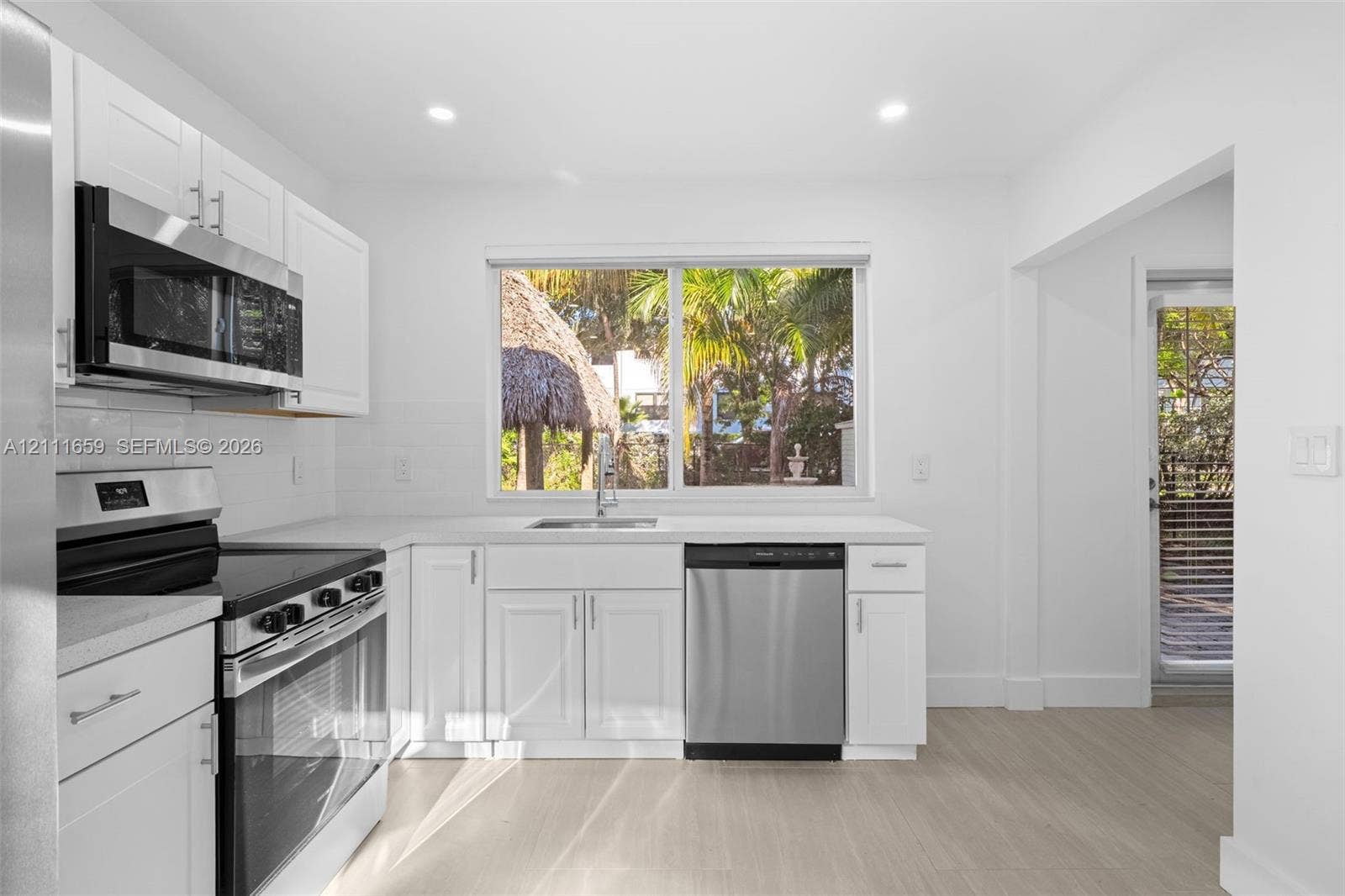 338 Taylor Street, #2, Hollywood, Hollywood, FL 33019 Kitchen featuring white shaker-style cabinetry, stainless steel appliances, solid-surface countertops, recessed lighting, and wood-finish flooring