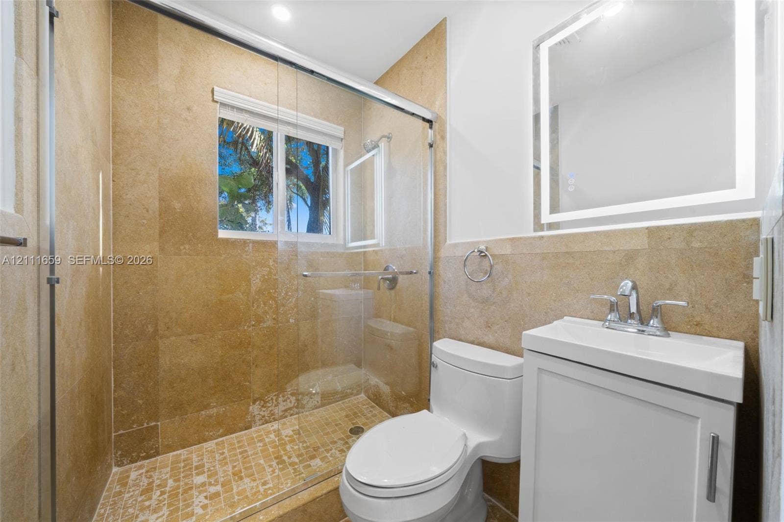 338 Taylor Street, #2, Hollywood, Hollywood, FL 33019 Bathroom featuring stone tile shower walls with an integrated glass enclosure, custom-lit vanity mirror, white cabinetry, and mosaic tile shower flooring