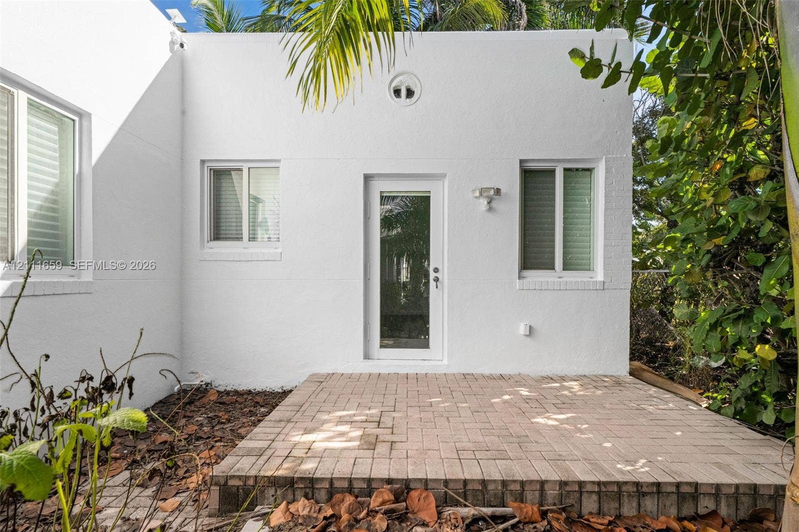 338 Taylor Street, #2, Hollywood, Hollywood, FL 33019 Exterior featuring a white stucco facade, brick paver patio, full-glass panel door, and dual-pane windows