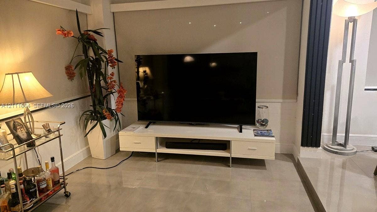 White built-in media console with storage drawers, polished tile flooring, and neutral wall tones