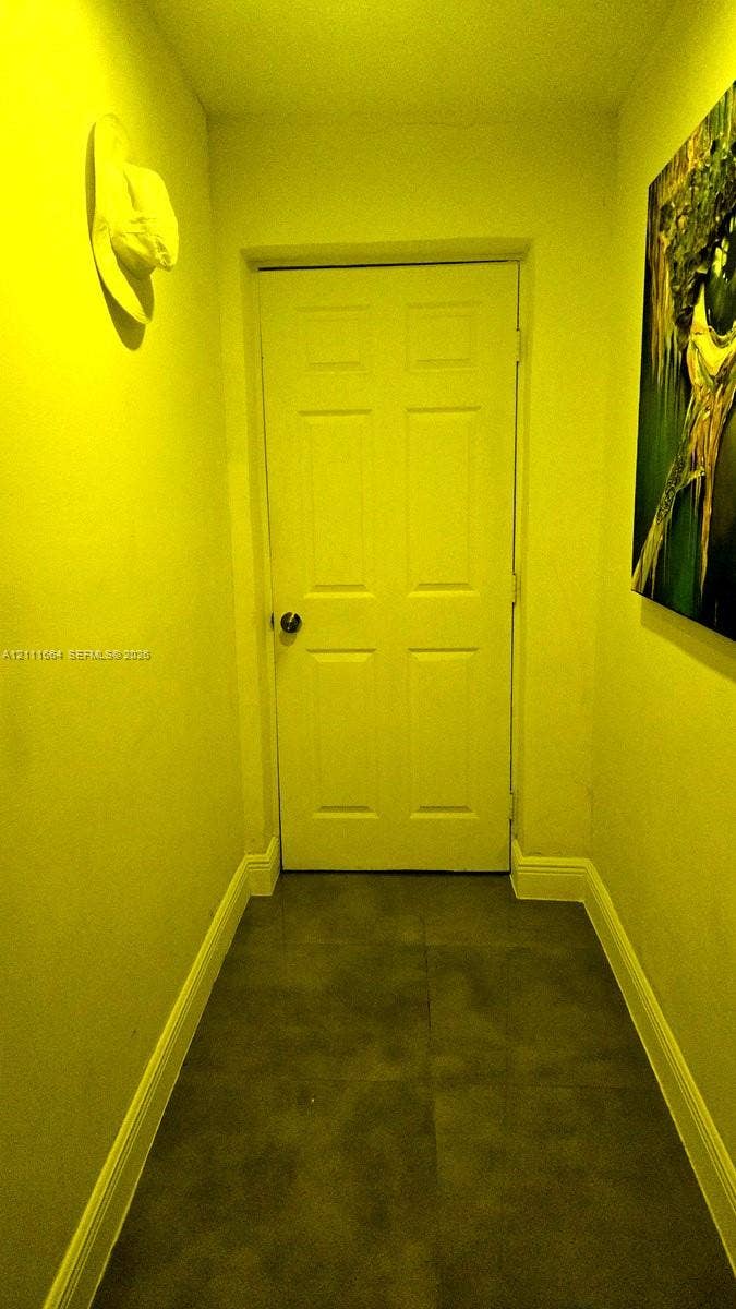 Six-panel interior door with brushed metal hardware and large-format tile flooring