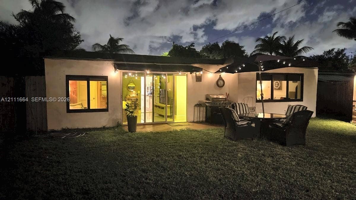 Rear exterior featuring a sliding glass door, dark-framed windows, and an expansive lawn