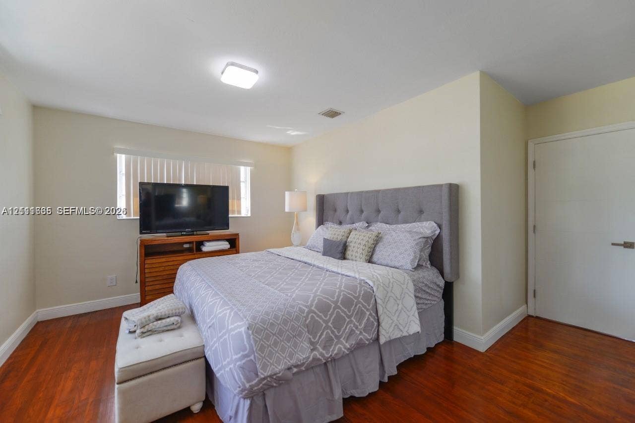 Room featuring wood-finish flooring, neutral wall paint, and a window with horizontal blinds