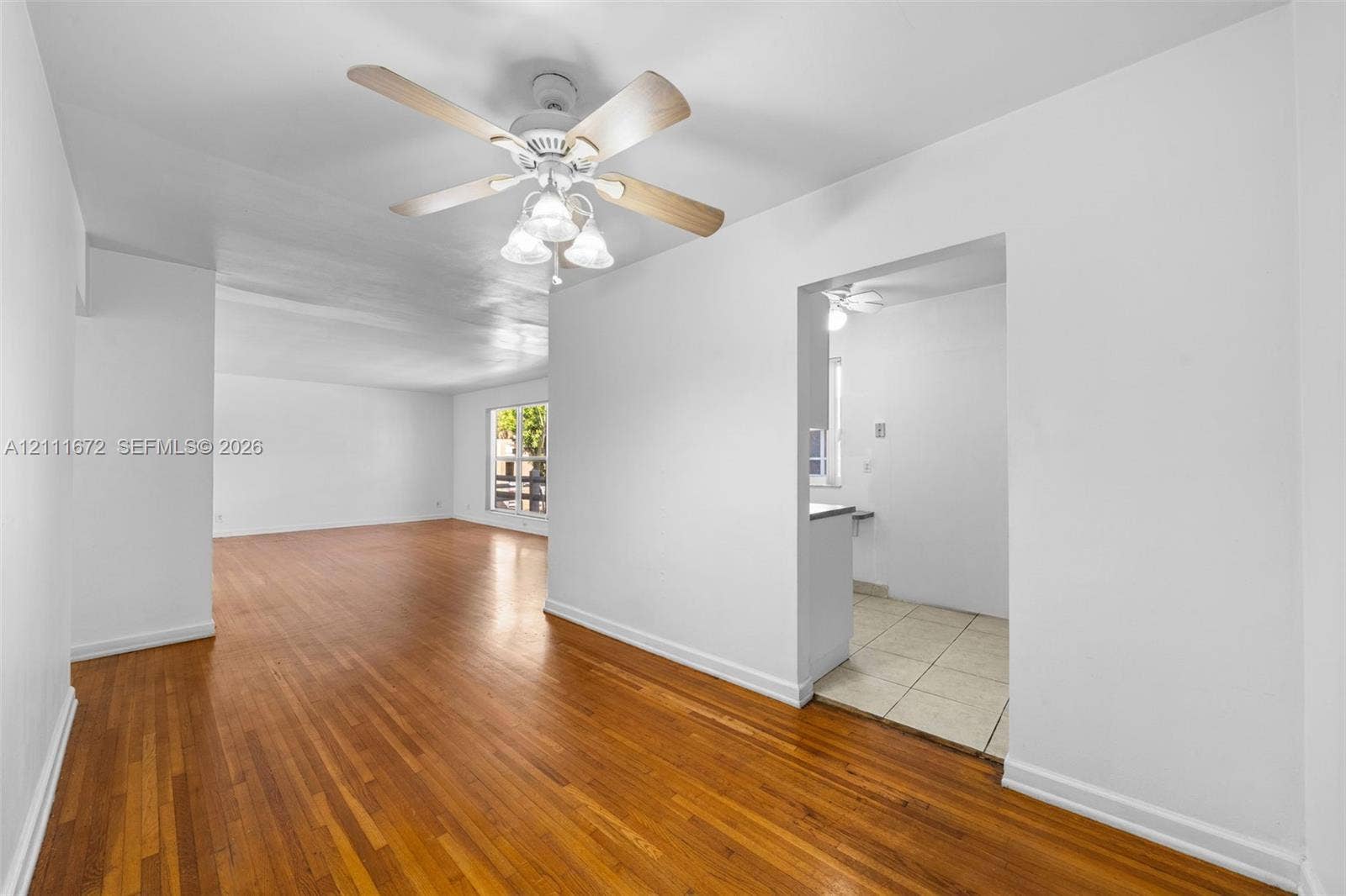 Interior space featuring wood-finish flooring, white walls, and a ceiling-mounted light fixture with a fan