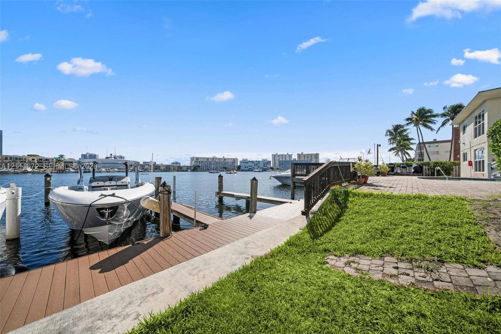 Waterfront property featuring a private boat dock, composite decking, paver patio, and lawn space