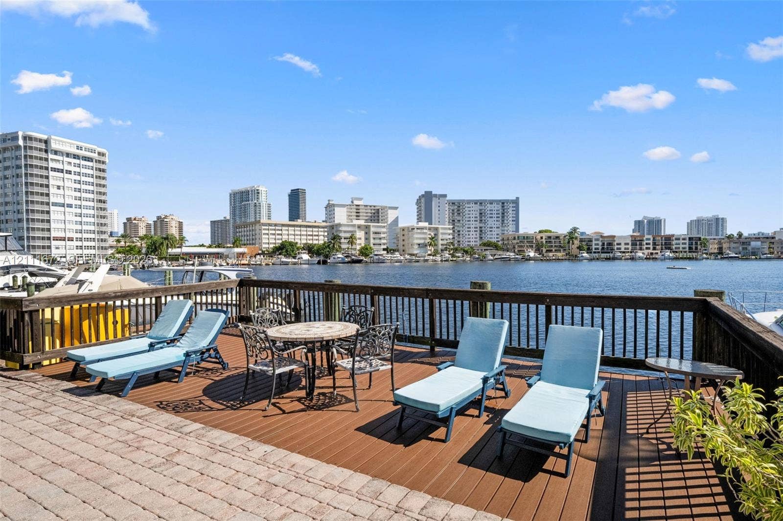 Waterfront terrace featuring composite decking, paved hardscaping, and a wooden perimeter railing