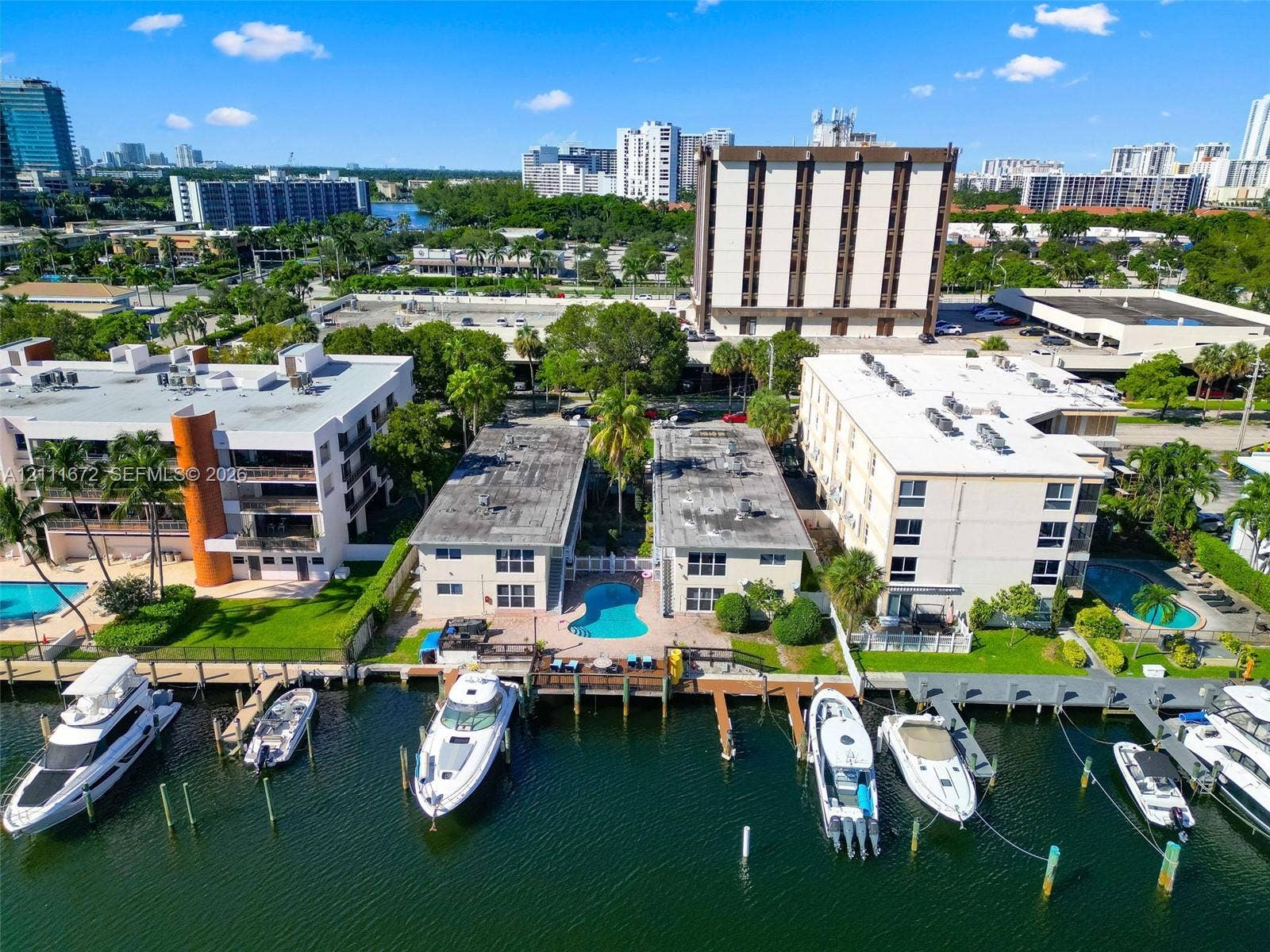 Waterfront multi-family property featuring private boat slips, a swimming pool, concrete seawall, and landscaped grounds
