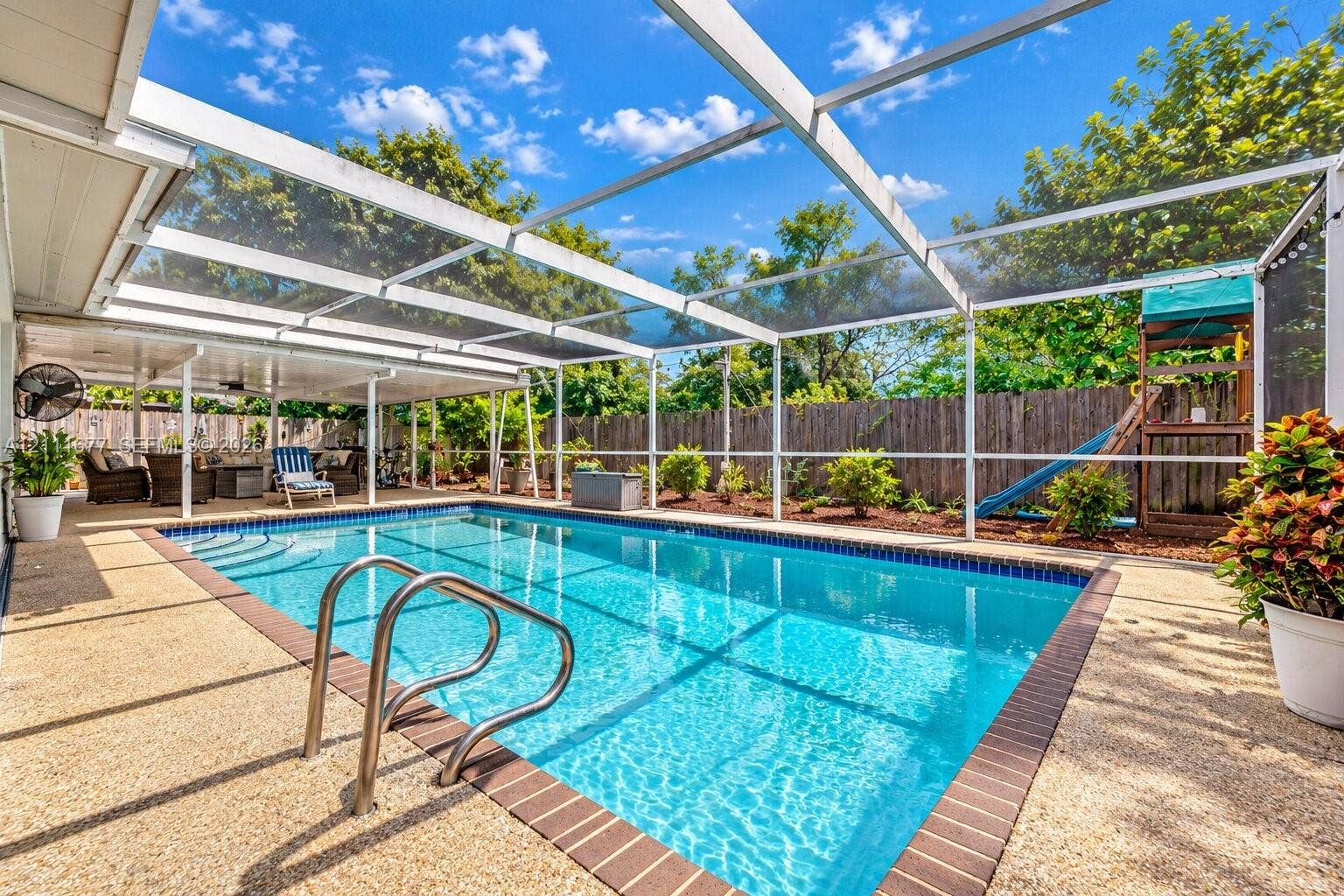 1921 Acapulco Drive, Miramar, FL 33023 Screened-in pool area featuring a pebble-finish pool deck, brick coping, stainless steel ladder, and a covered lanai