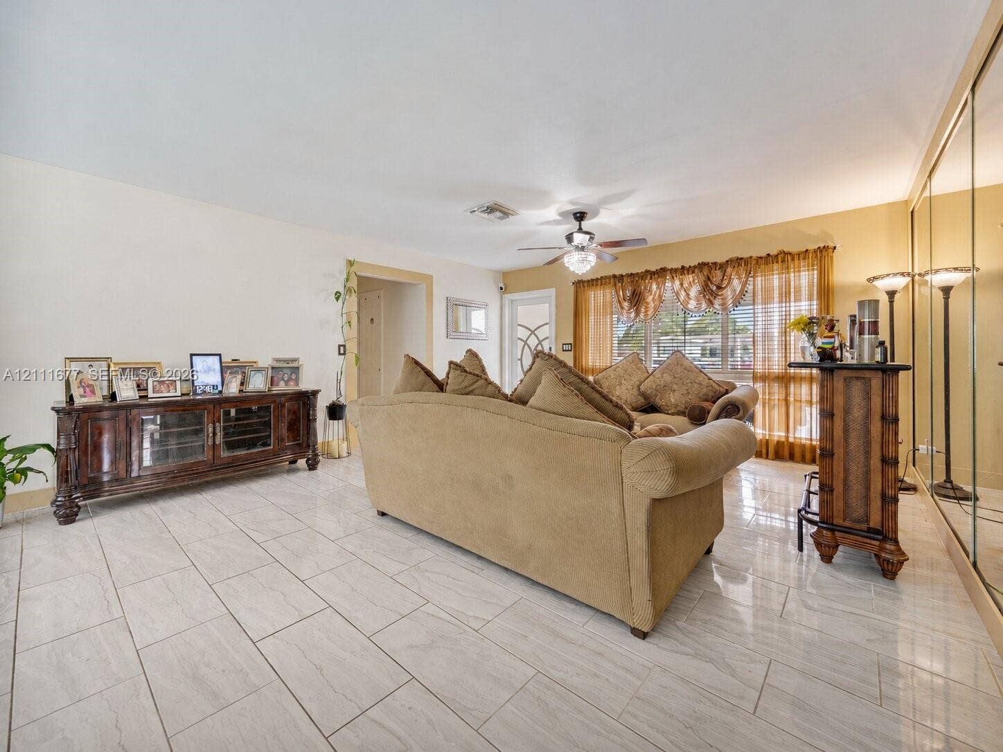 1921 Acapulco Drive, Miramar, FL 33023 Neutral-toned tile flooring, mirrored wall paneling, ceiling-mounted light fixture, and windows with integrated grid patterns