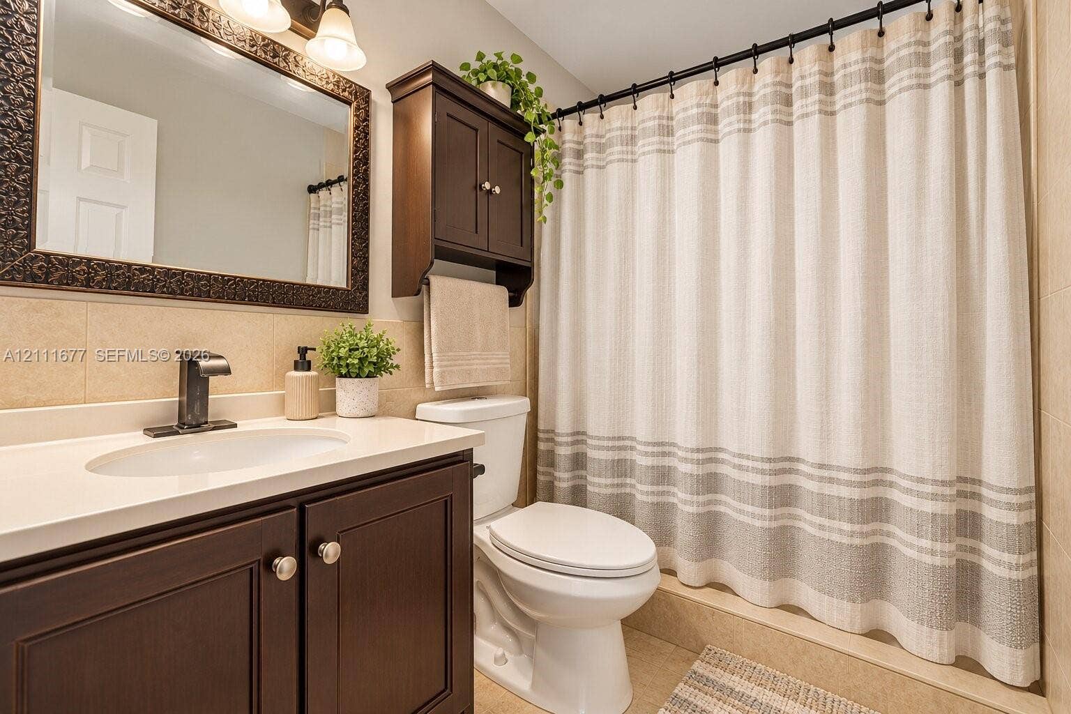 1921 Acapulco Drive, Miramar, FL 33023 Bathroom vanity featuring dark-toned cabinetry, a solid-surface countertop with an integrated basin, a wall-mounted medicine cabinet, and a single-handle matte black faucet