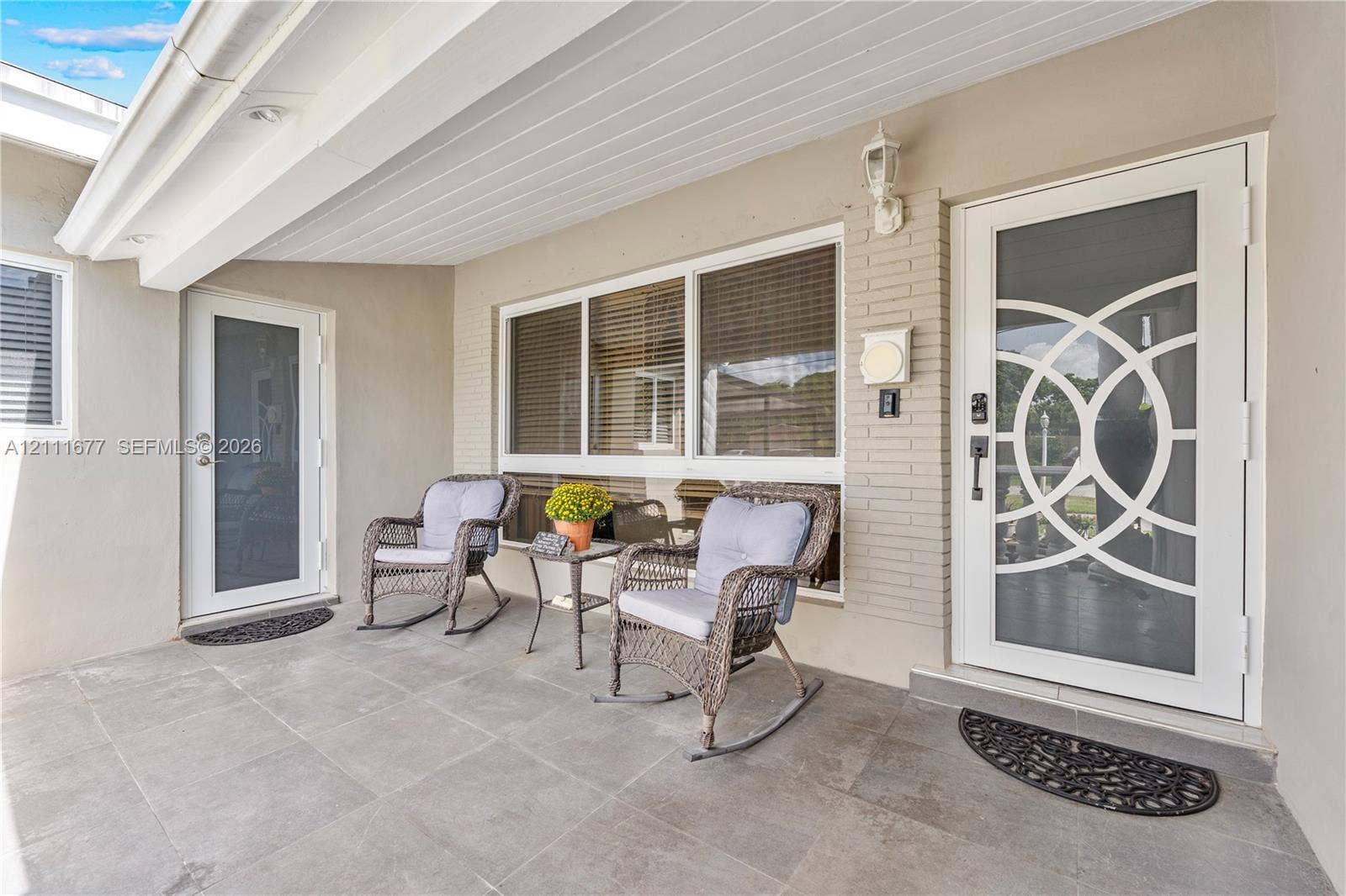 1921 Acapulco Drive, Miramar, FL 33023 Covered porch featuring large-format tile flooring, white brick accents, and two exterior doors with decorative circular-patterned glass inserts