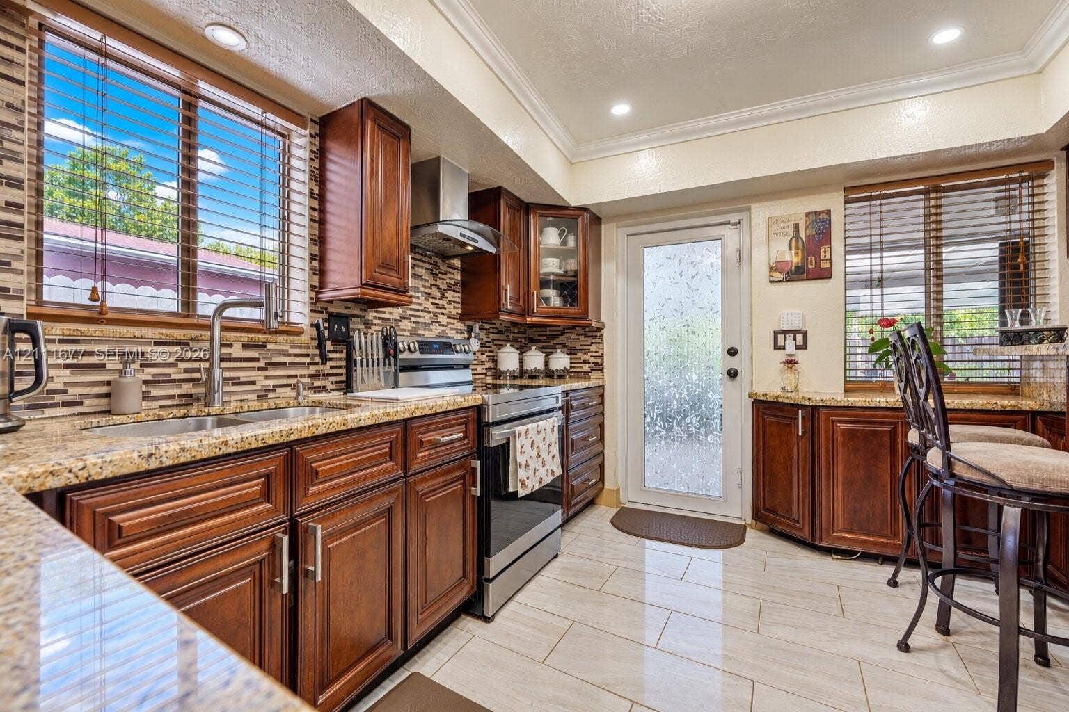 1921 Acapulco Drive, Miramar, FL 33023 Kitchen featuring dark wood cabinetry, stone countertops, a mosaic tile backsplash, stainless steel appliances, and tile flooring