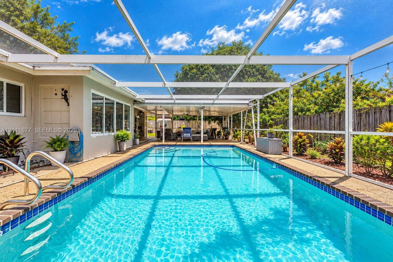 1921 Acapulco Drive, Miramar, FL 33023 Screened lanai featuring a swimming pool, tiled pool coping, metallic handrails, and a covered patio area