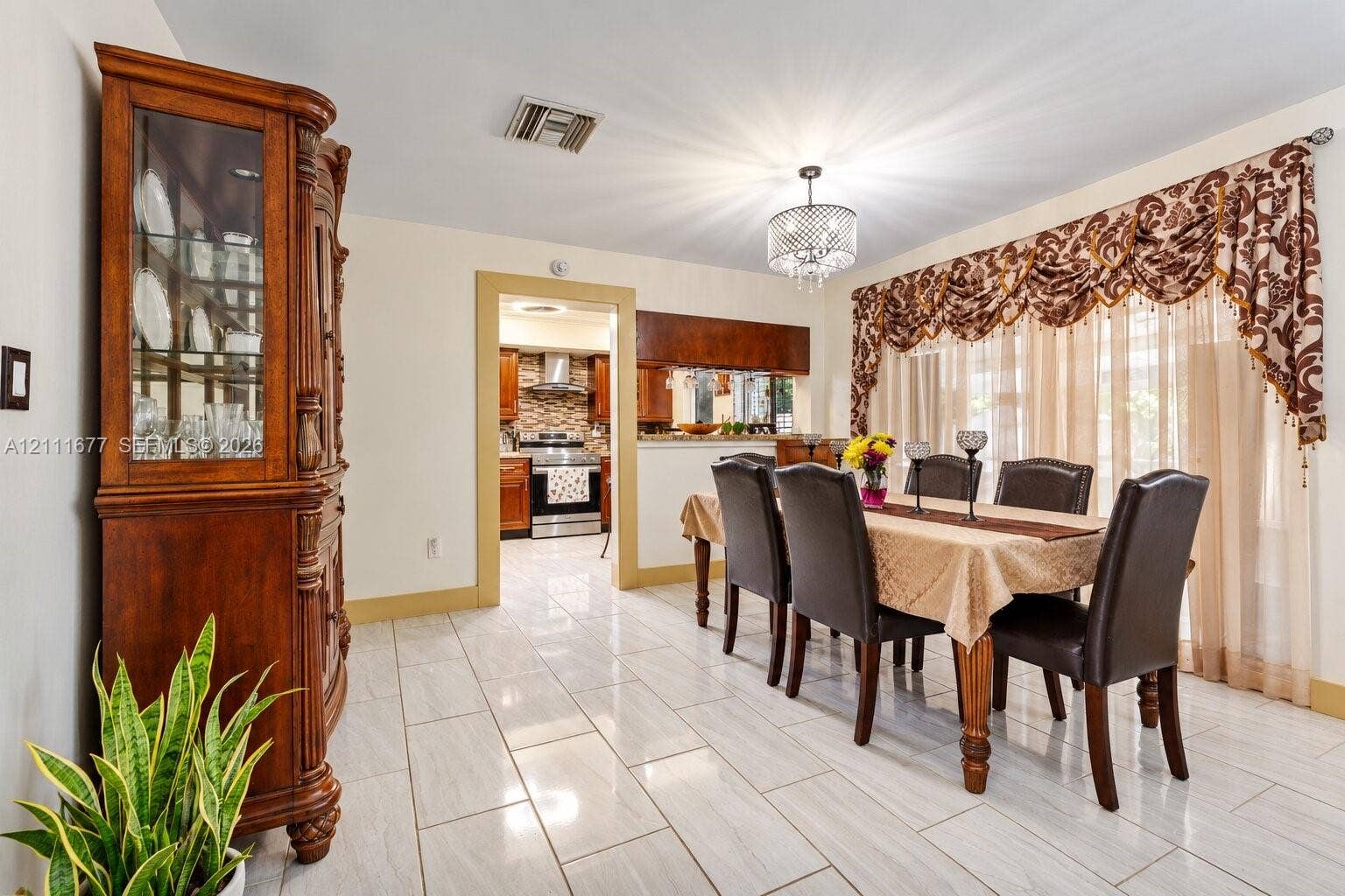 1921 Acapulco Drive, Miramar, FL 33023 Dining area featuring neutral tile flooring, a crystal-accented chandelier, and expansive windows