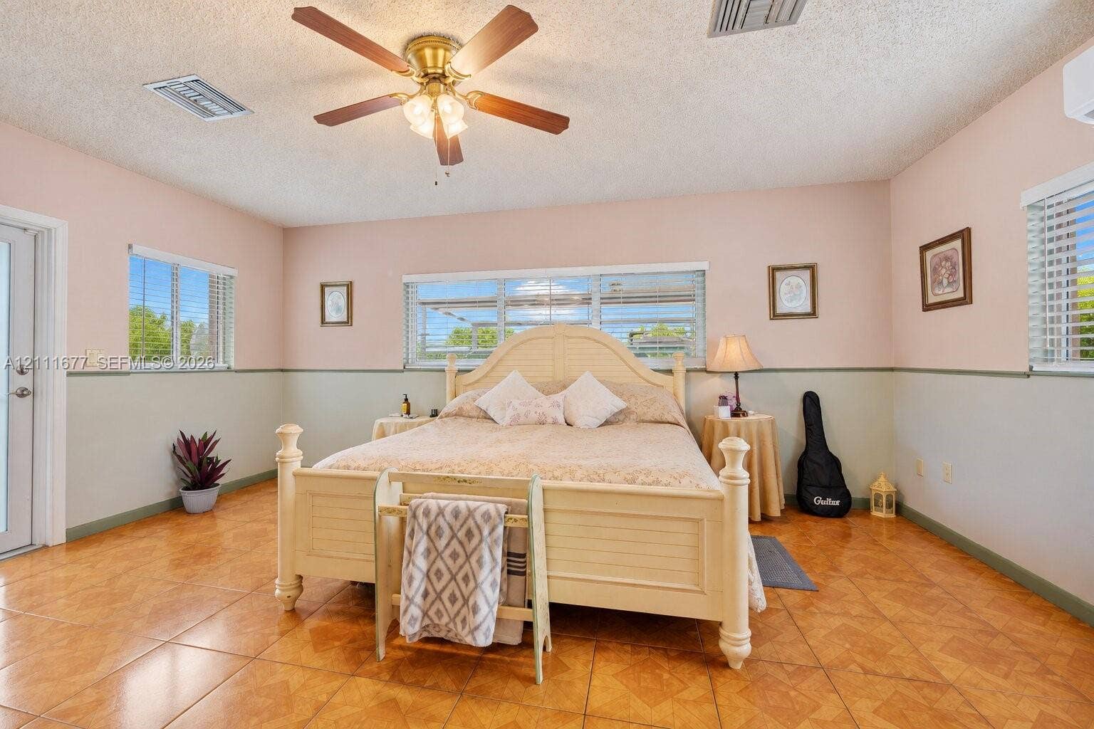 1921 Acapulco Drive, Miramar, FL 33023 Spacious room featuring large-format ceramic tile flooring, neutral wall paneling with a chair rail, multi-pane windows, and a ceiling fan with integrated lighting