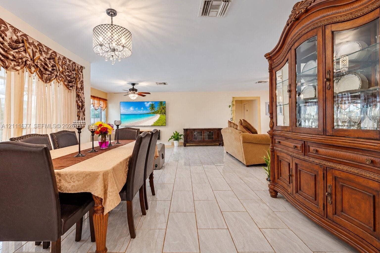 1921 Acapulco Drive, Miramar, FL 33023 Open-concept room featuring light-toned tile flooring, a multi-tier crystal chandelier, and a ceiling fan with integrated lighting