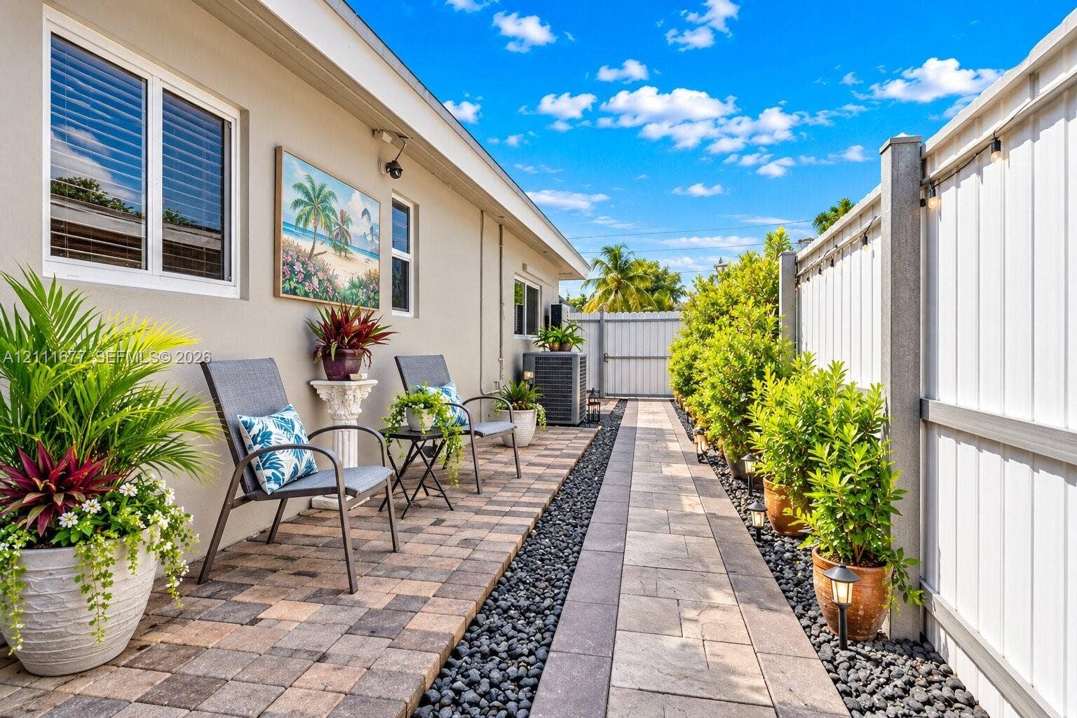 1921 Acapulco Drive, Miramar, FL 33023 Exterior side yard featuring multi-toned paver hardscaping, decorative stone border, and a privacy fence