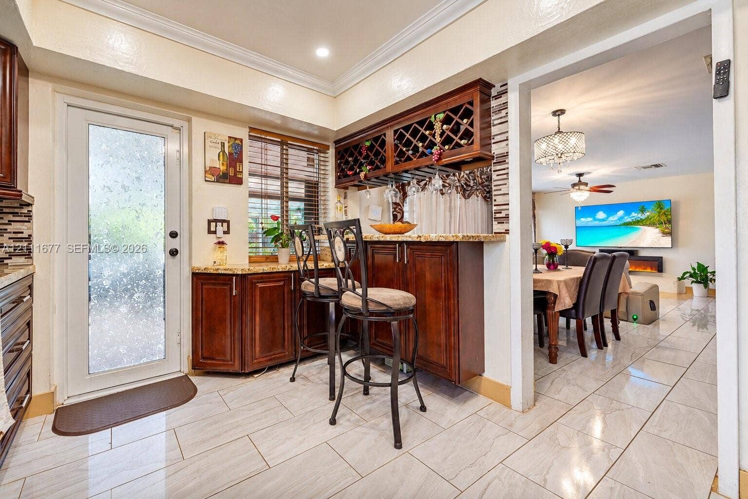 1921 Acapulco Drive, Miramar, FL 33023 Kitchen featuring wood cabinetry with built-in wine rack, stone countertops, tiled flooring, and a glass-paneled exterior door