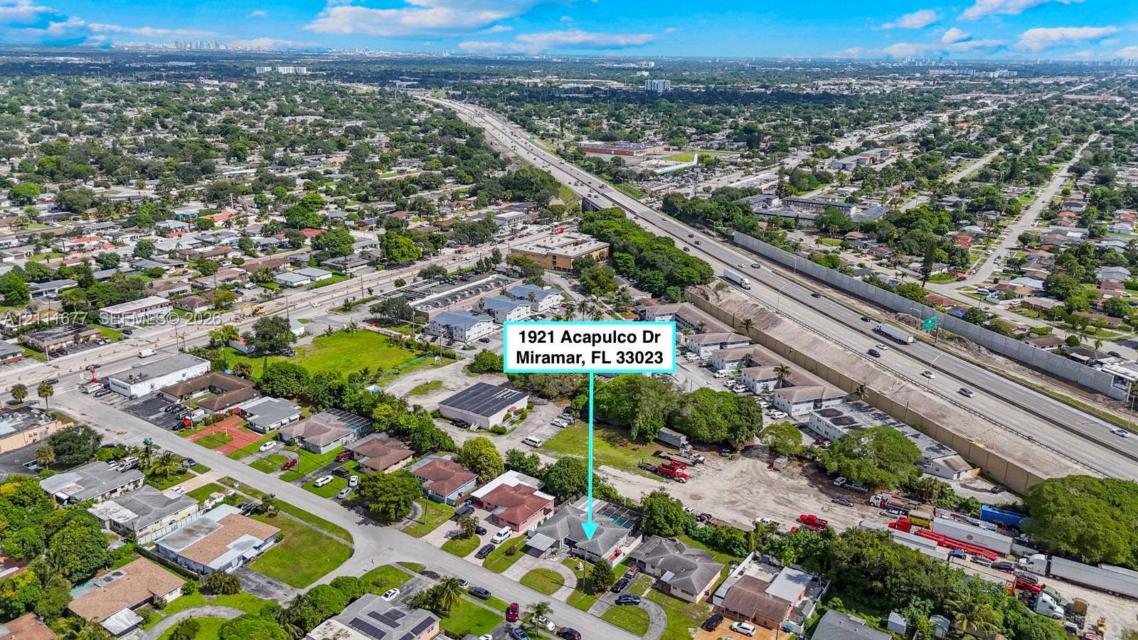 1921 Acapulco Drive, Miramar, FL 33023 Aerial perspective of a single-story residence with a concrete-tiled roof and an attached carport, situated on a lot featuring mature trees and landscaped grounds