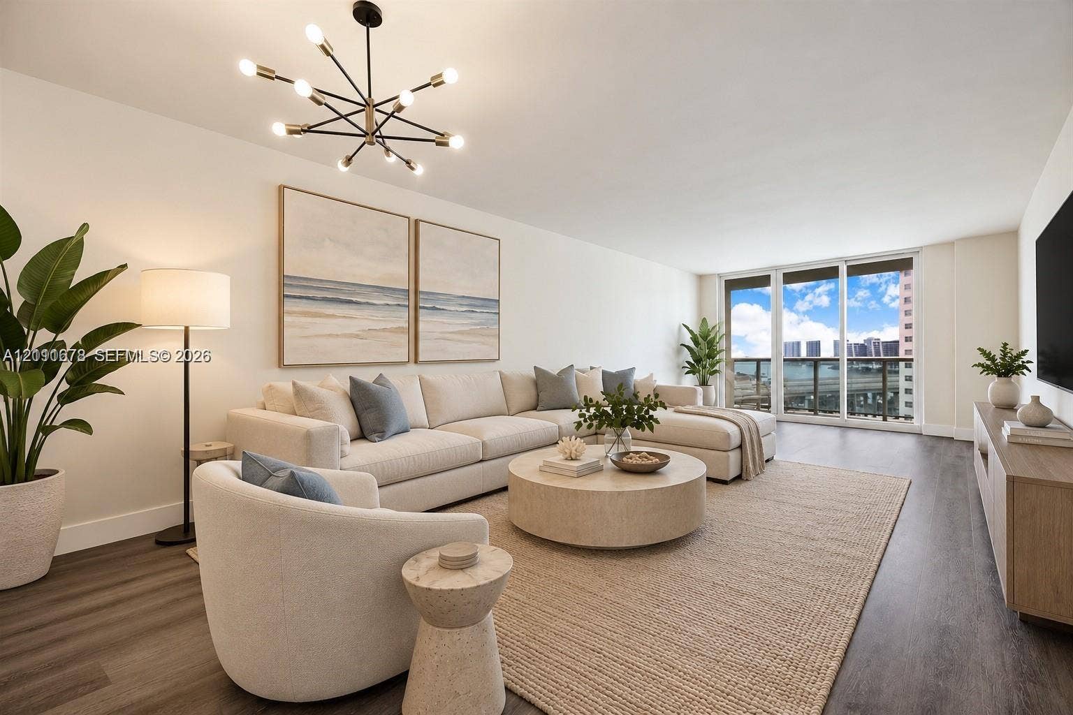 Spacious interior featuring wood-finish flooring, a modern multi-arm chandelier, and floor-to-ceiling glass sliding doors opening to a balcony