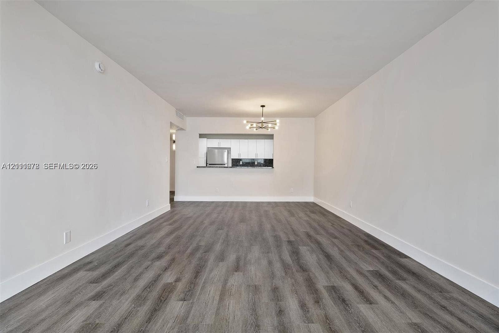 Interior space featuring wood-finish flooring, a contemporary multi-arm chandelier, and a pass-through opening to the kitchen