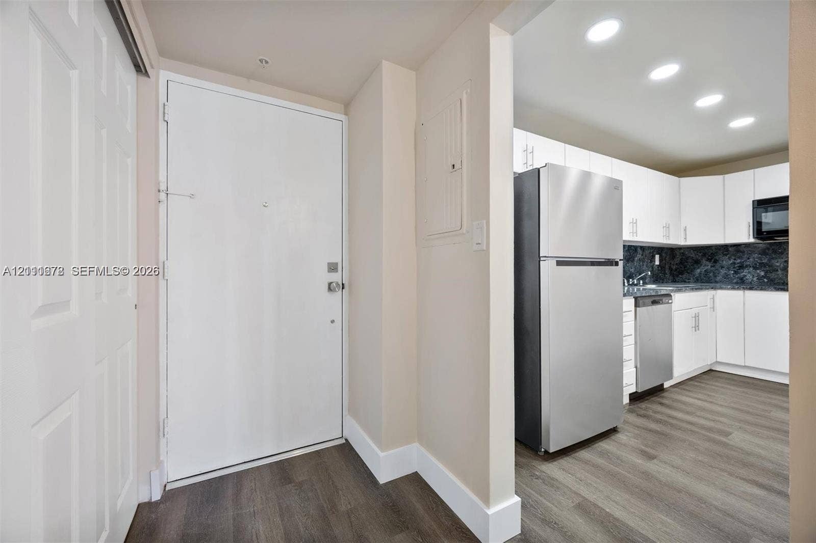 Kitchen area featuring white cabinetry, stone-finish countertops, stainless steel appliances, and wood-finish flooring with recessed lighting
