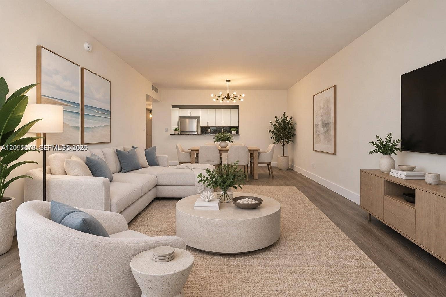 Open-concept living area featuring wood-finish flooring, a contemporary multi-arm chandelier, and a pass-through kitchen opening
