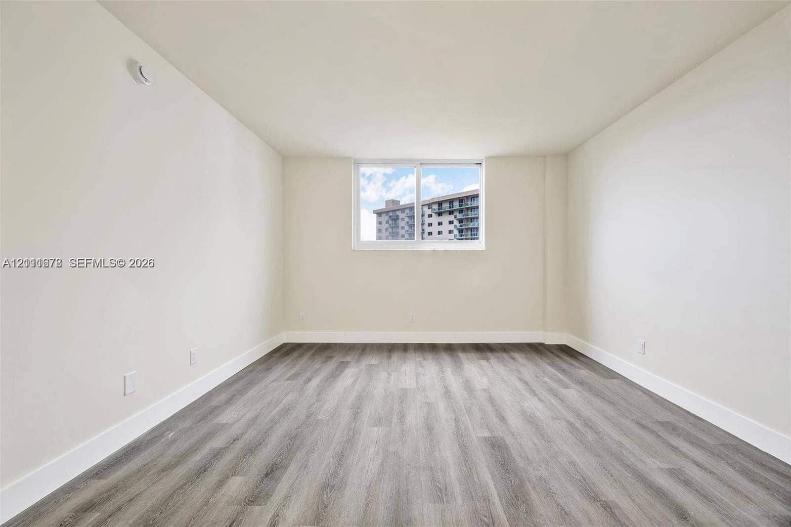 Interior space featuring neutral-toned walls, wood-finish flooring, and a sliding window