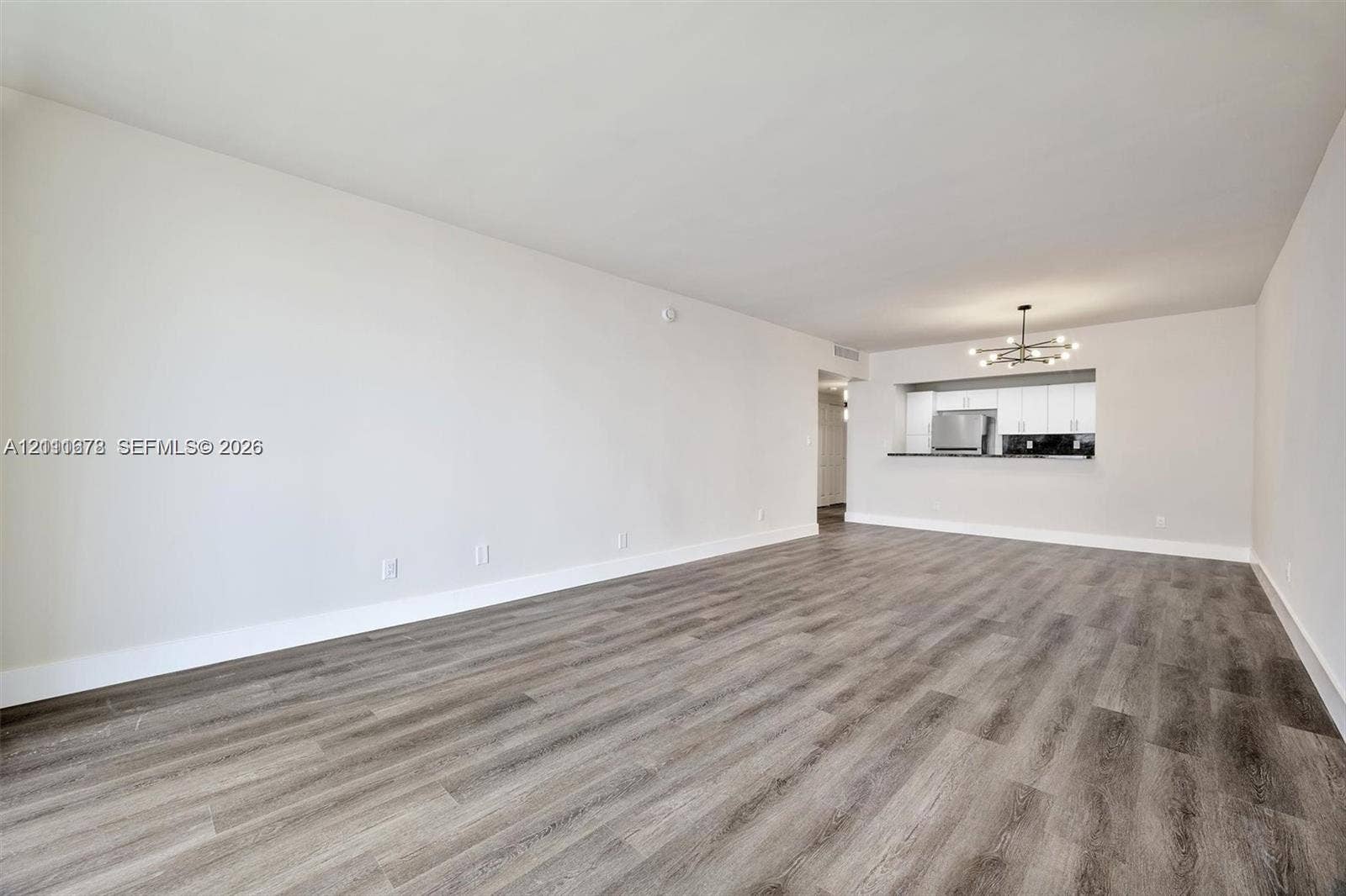 Living space featuring wood-finish flooring, recessed ceiling lighting, and a kitchen pass-through window with an integrated breakfast bar