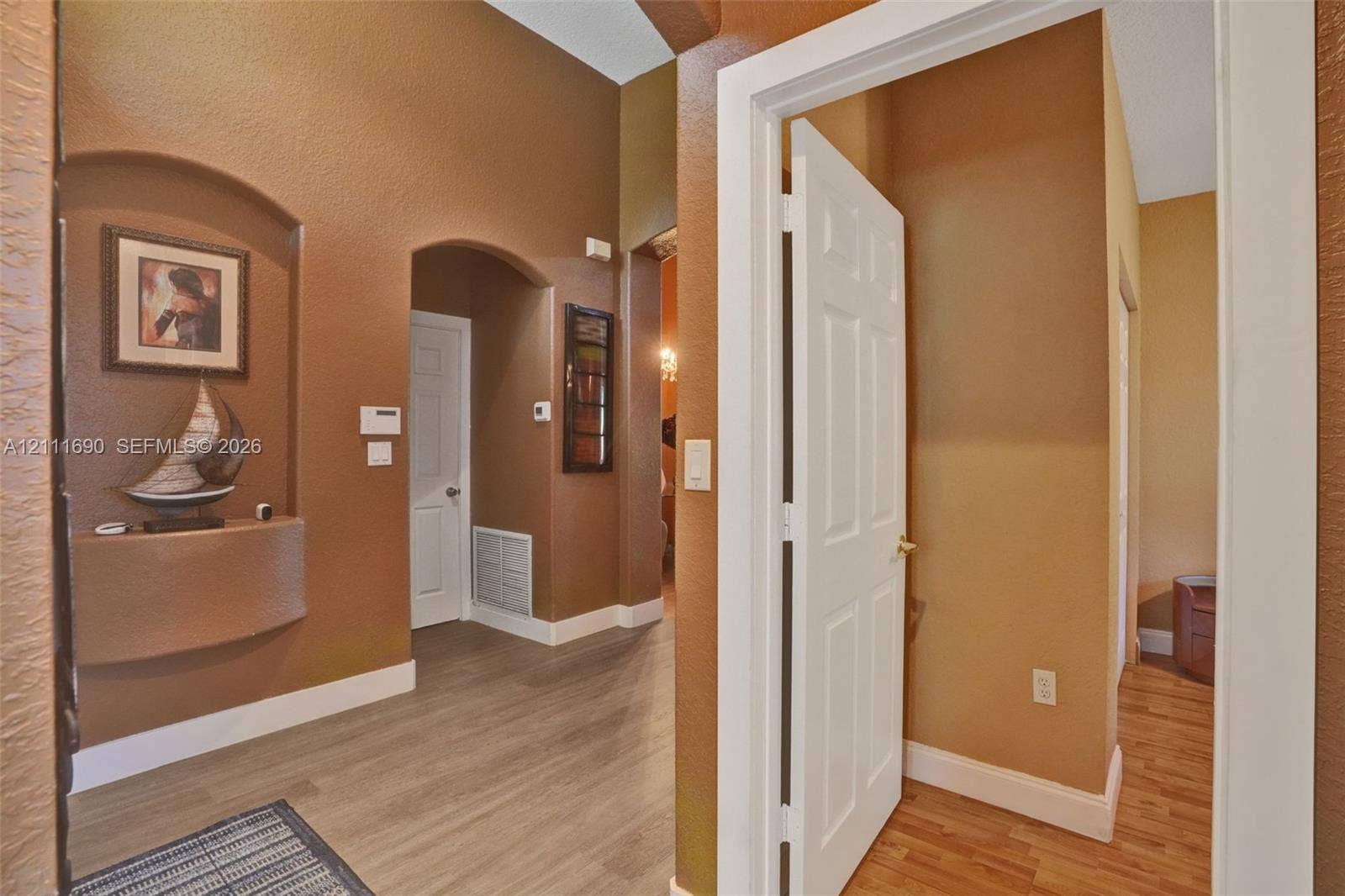 Entryway featuring vaulted ceilings, arched wall niches, multi-panel doors, and wood-finish flooring