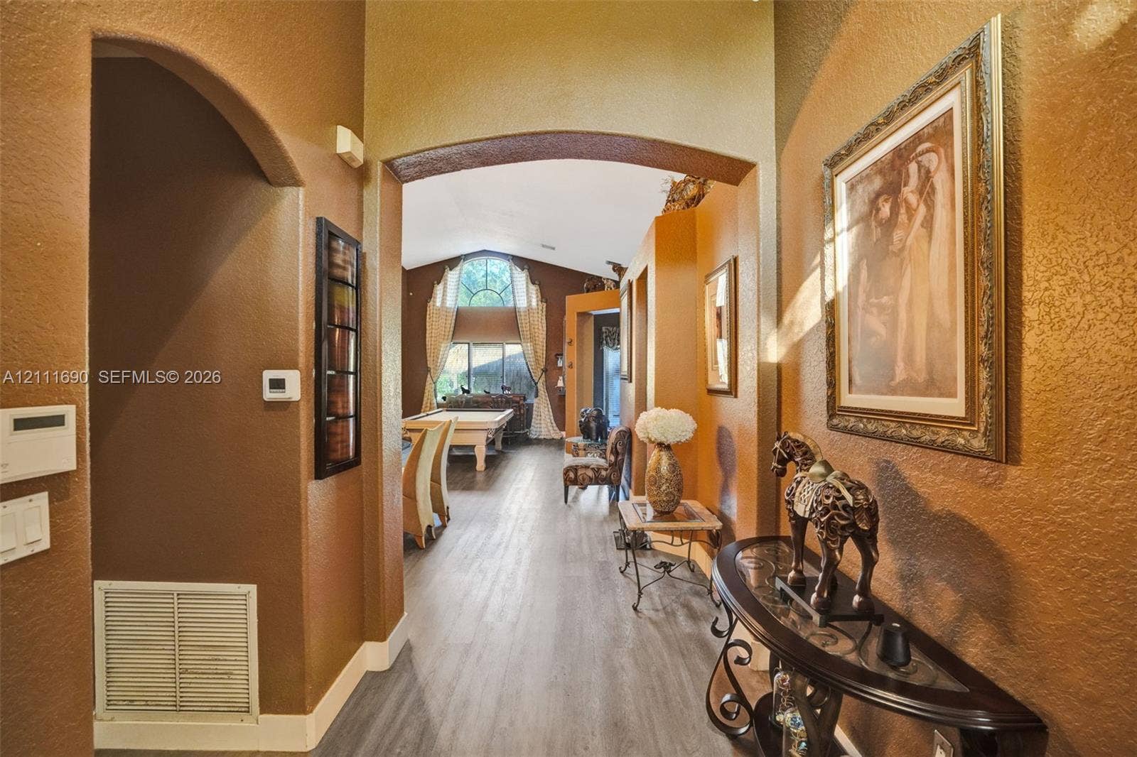 Entryway featuring arched architectural detailing, wood-finish flooring, and high ceilings with an expansive arched window