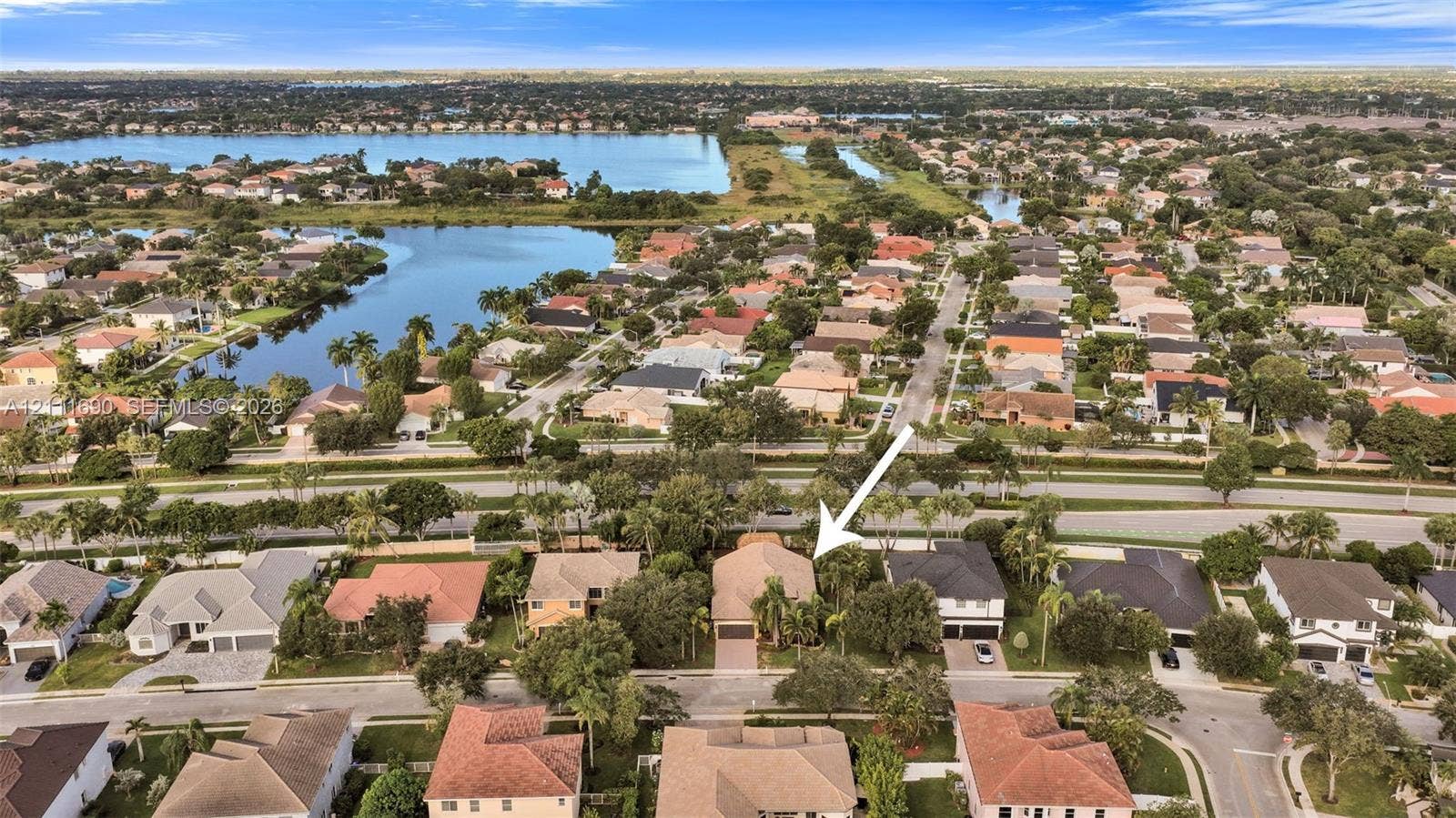 Aerial perspective of a single-story residence featuring a tile roof, paved driveway, and mature landscaping