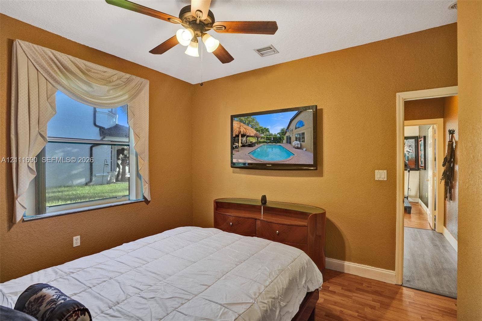 Room featuring wood-finish flooring, a multi-blade ceiling fan with integrated lighting, and a single-hung window