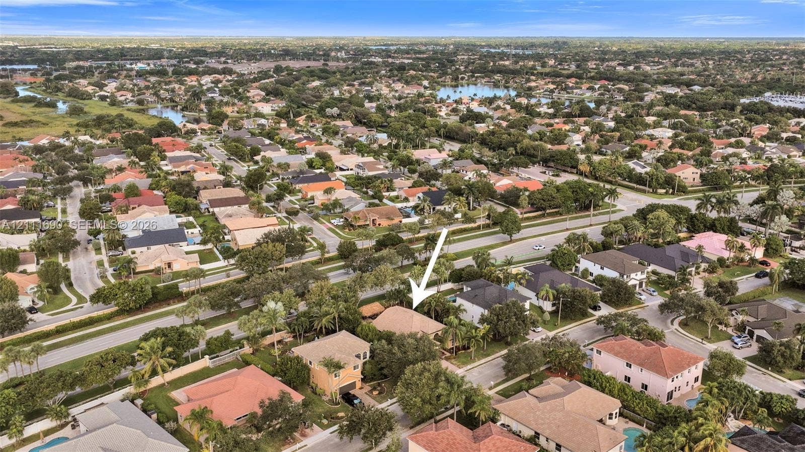 Aerial perspective of a single-story residence featuring a hipped roofline, mature landscaping, and an attached multi-car garage