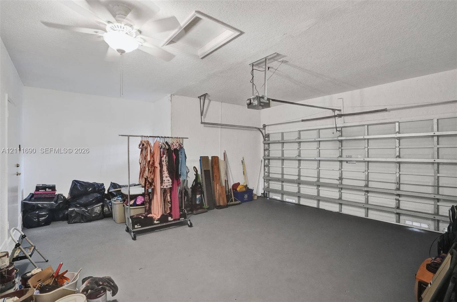 Garage interior featuring painted concrete flooring, an overhead automatic door opener, and a ceiling-mounted light fixture
