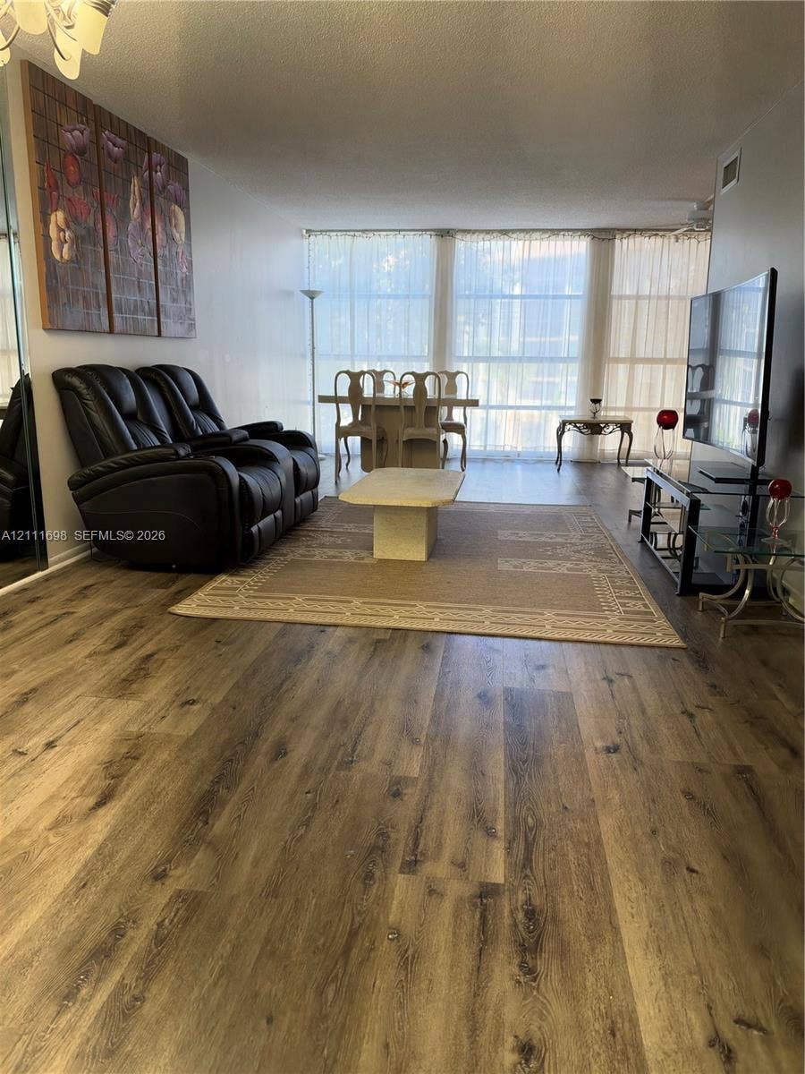 601 Three Islands Boulevard, #308, Hallandale Beach, Hallandale Beach, FL 33009 Living area featuring wood-finish flooring, floor-to-ceiling windows, and a mirrored closet wall