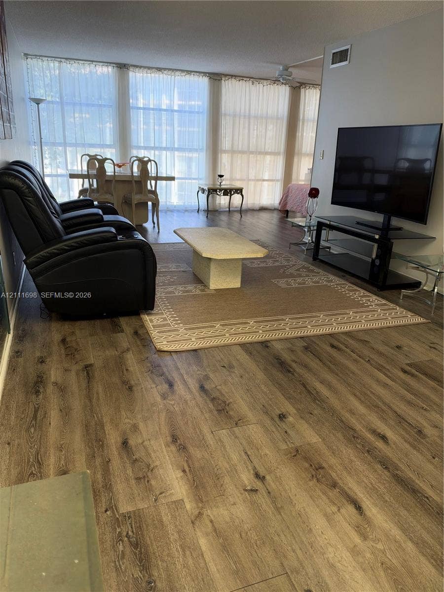 601 Three Islands Boulevard, #308, Hallandale Beach, Hallandale Beach, FL 33009 Open living space featuring wood-finish flooring and floor-to-ceiling windows