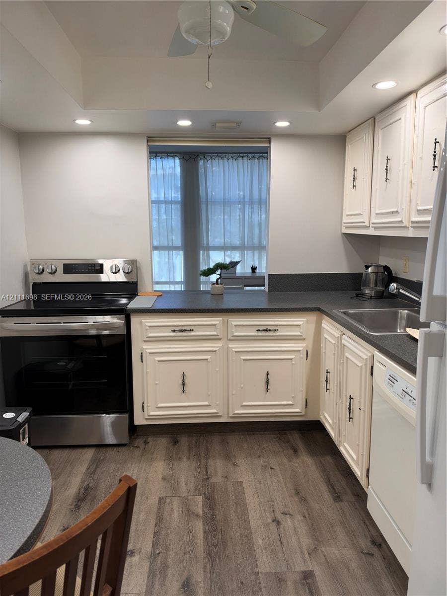 601 Three Islands Boulevard, #308, Hallandale Beach, Hallandale Beach, FL 33009 Kitchen featuring recessed lighting, wood-finish flooring, dark solid-surface countertops, paneled cabinetry, and stainless steel appliances
