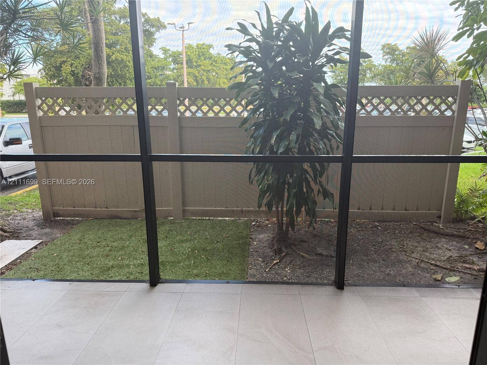 Screened patio featuring large format tile flooring and a vinyl privacy fence with lattice detailing