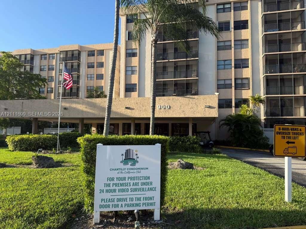 Multi-story residential building exterior featuring a covered porte-cochre, private screened balconies, and landscaped grounds