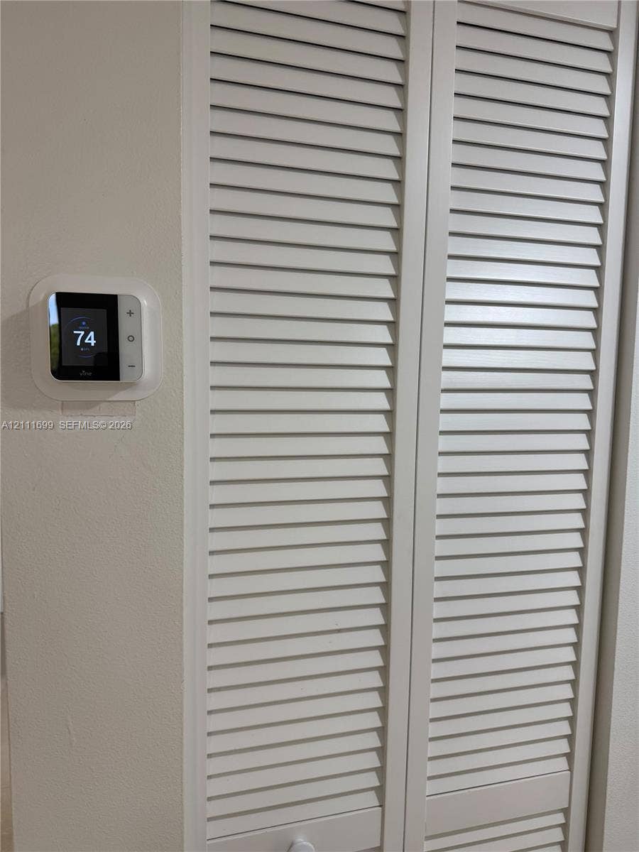 Digital smart thermostat and white bi-fold louvered closet doors