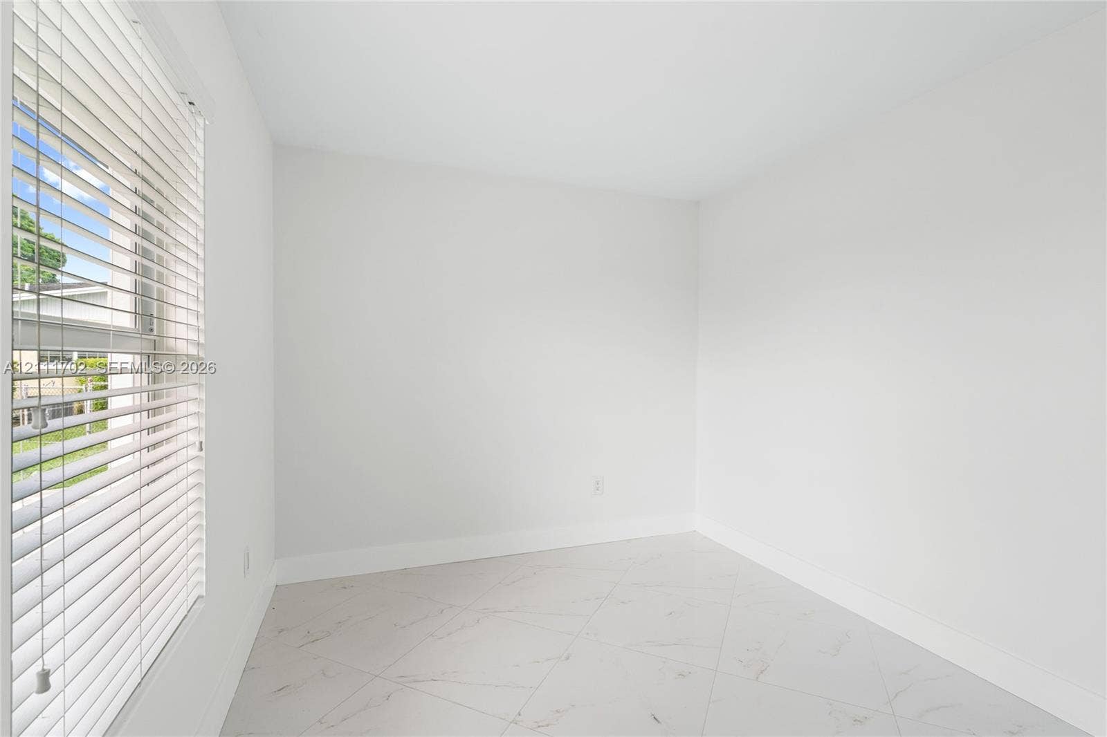 Neutral-toned room featuring large-format tile flooring and horizontal window blinds