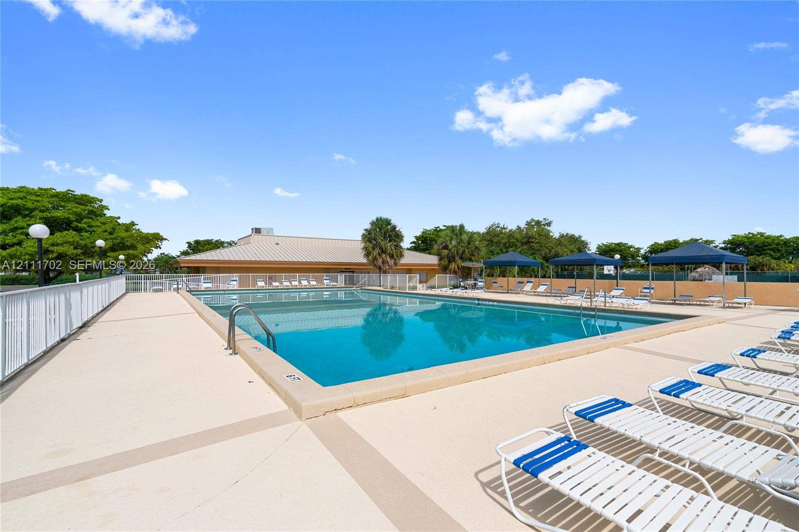 Rectangular swimming pool with metal ladder entry, concrete deck, and perimeter safety fencing
