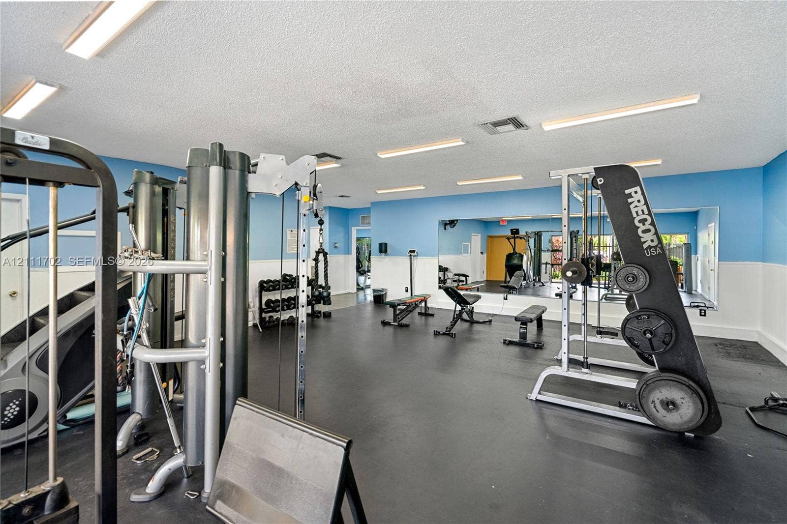 Fitness center featuring rubberized flooring, large wall-mounted mirrors, and recessed ceiling lighting