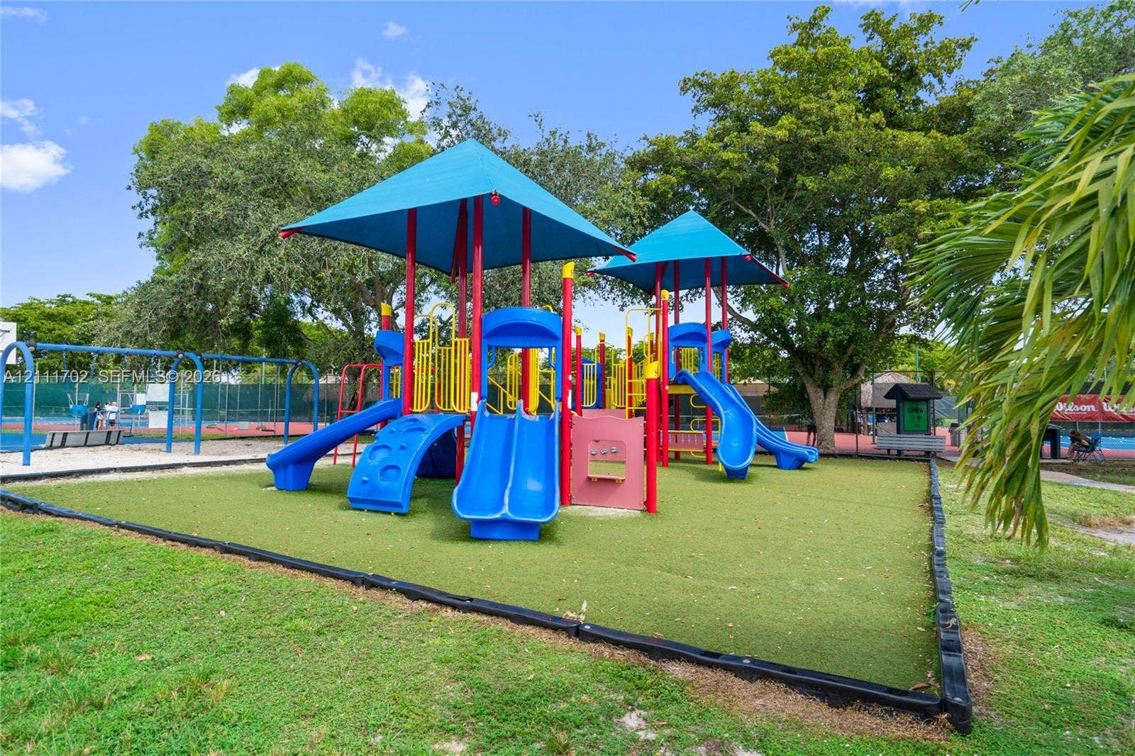 Playground featuring multi-level structures, shade canopies, integrated slides, and synthetic grass surfacing