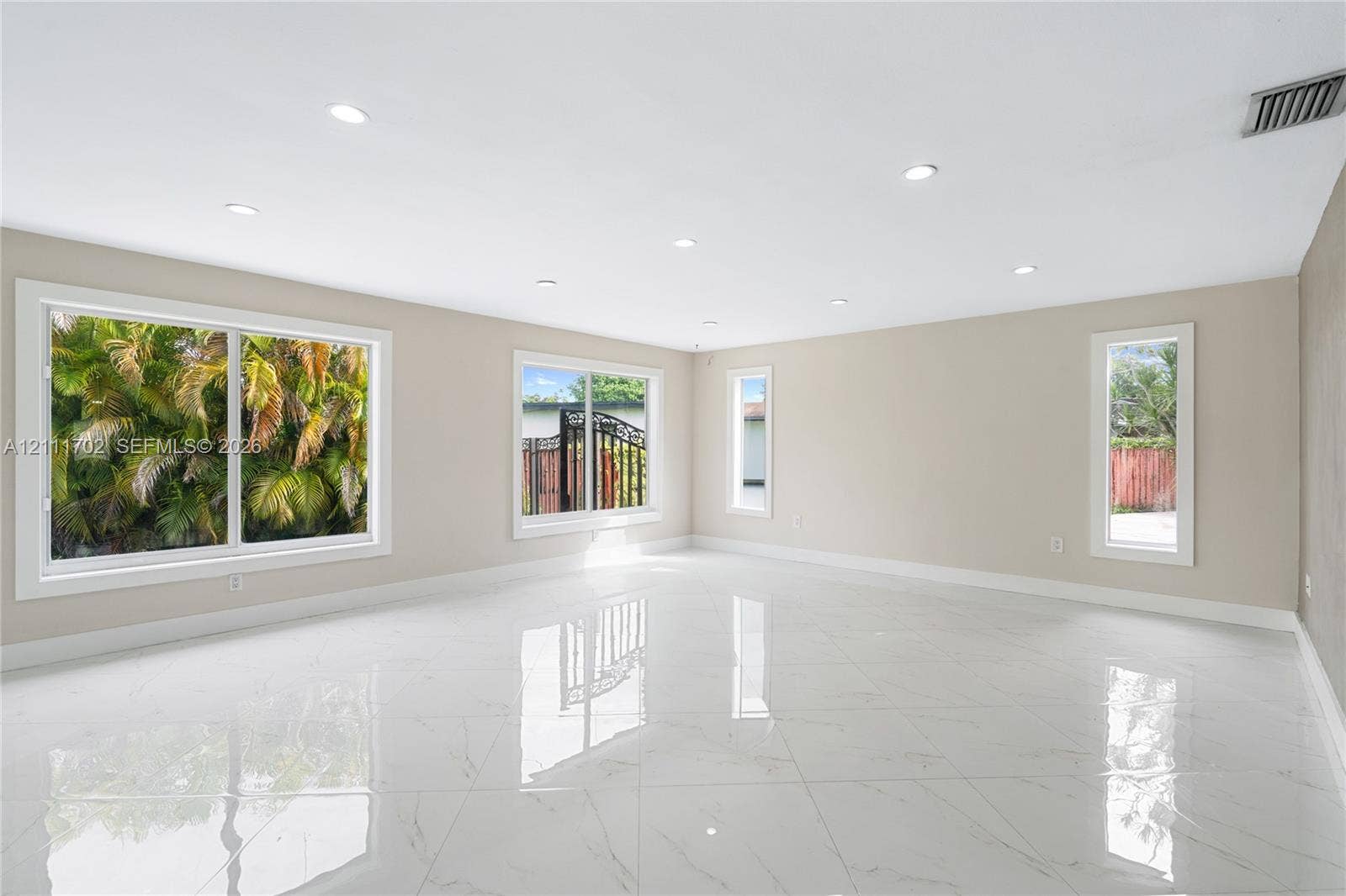 Neutral-toned interior featuring large-format polished tile flooring, recessed lighting, and multiple windows providing natural light